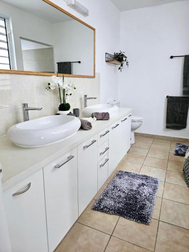 a white bathroom with a sink and a mirror at Cozy House in a private complex in Paea