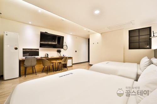 a hotel room with two beds and a desk at Brown Dot Hotel Guun in Suwon