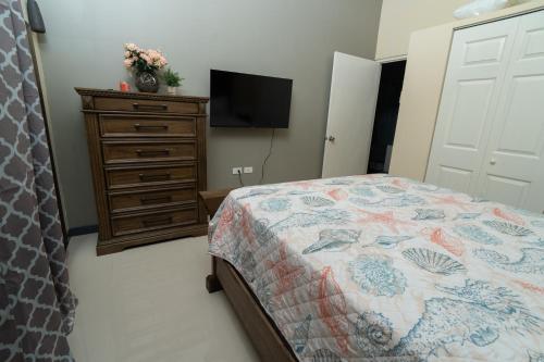 a bedroom with a bed and a dresser with a television at Sky View Villas @ Edmund Ridge Estate in Montego Bay