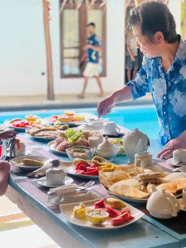 a woman standing at a table with plates of food at Maritime Nest Cabanas in Tangalle