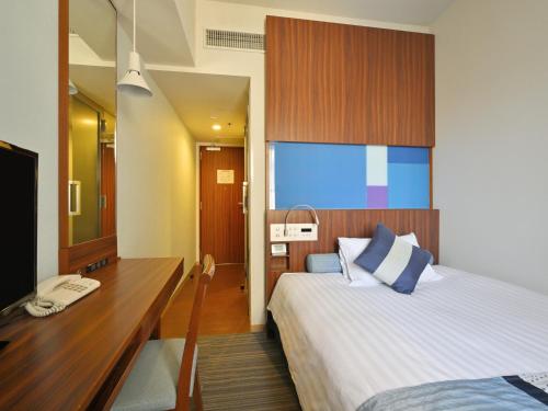 a bedroom with a bed and a desk and a television at Rihga Hotel Zest Takamatsu in Takamatsu