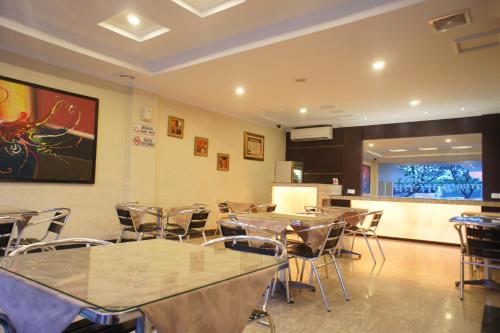a dining room with tables and chairs and a kitchen at Sky View Hotel Managed by OS in Batam Center