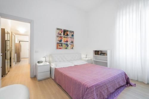 a white bedroom with a bed with a purple blanket at Appartamento incantevole con patio in Florence