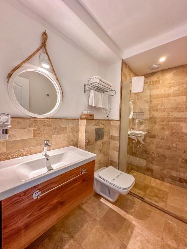 a bathroom with a sink and a toilet and a mirror at Ayvalık Sea Resort in Ayvalık