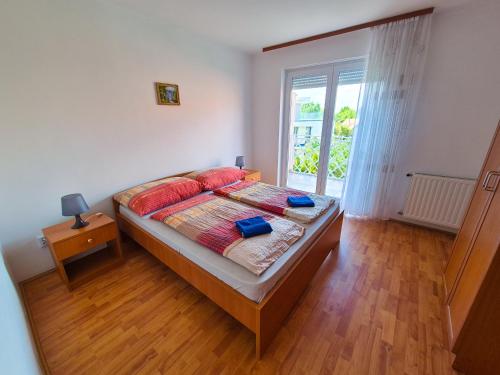 sypialnia z łóżkiem z czerwonymi poduszkami i oknem w obiekcie Ildiko Apartmanhaz w Zamárdi