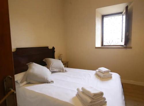 a bedroom with a white bed with towels on it at CA L'HERBOLARI - Cozy house in Montseny in Viladrau