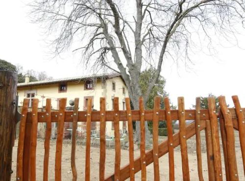 a wooden fence in front of a house with a tree at CA L'HERBOLARI - Cozy house in Montseny in Viladrau