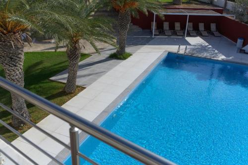 a swimming pool with palm trees next to a building at Porto Belissario in Ferma