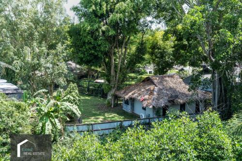 a small house with a thatched roof in a forest at Studio Apartment by the Sea E413 in Phuket Town