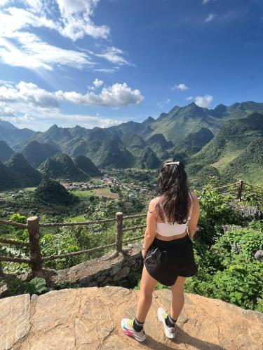 a woman standing on top of a cliff looking at the mountains at Strawberry House , Tour & Motorbikes Rentel in Ha Giang