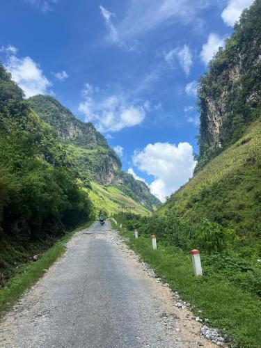 a road in the mountains with a person riding a motorcycle at Strawberry House , Tour & Motorbikes Rentel in Ha Giang