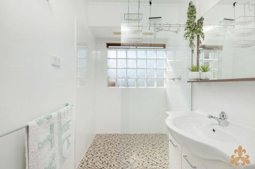 Un baño blanco con lavabo y espejo. en Oasis On Rice Street Downstairs, en Rockhampton