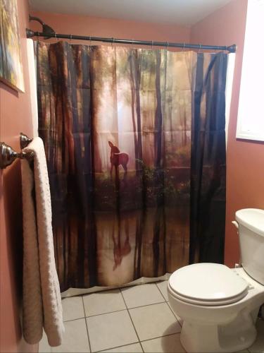 a bathroom with a shower curtain with a deer in the woods at Hidden LakeFront Retreat in Sherburne