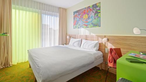 a bedroom with a white bed and a green desk at Hey Lou Hotel Hildesheim in Hildesheim