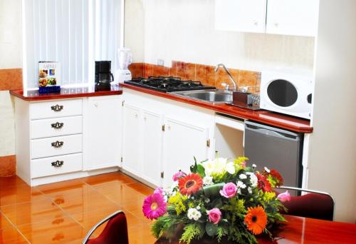 a kitchen with a table with a bouquet of flowers at Hotel Marcella Clase Ejecutiva in Morelia
