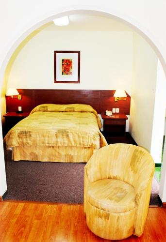 a bedroom with a bed and a chair at Hotel Marcella Clase Ejecutiva in Morelia