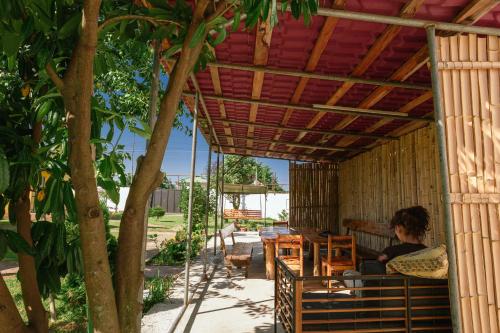 a woman sitting at a table under a pergola at Senima's paradise - Pool & Cottages in Batumi