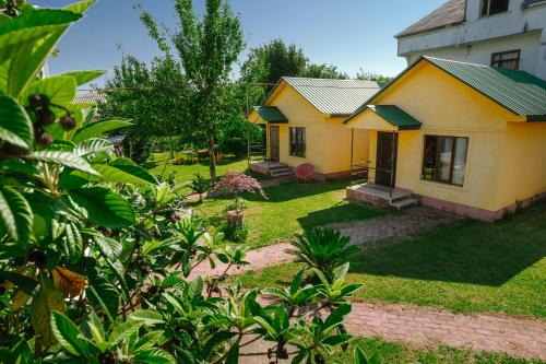 a small yellow house in a yard with trees at Senima's paradise - Pool & Cottages in Batumi