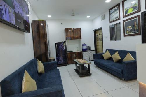 a living room with two blue couches and a table at Hari Home Stay in Garudeshwar