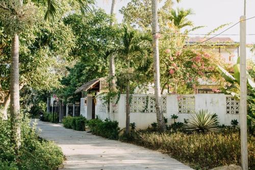 a white building with trees and a sidewalk at Bong Villa Hoi An - Vesta Collections in Hoi An