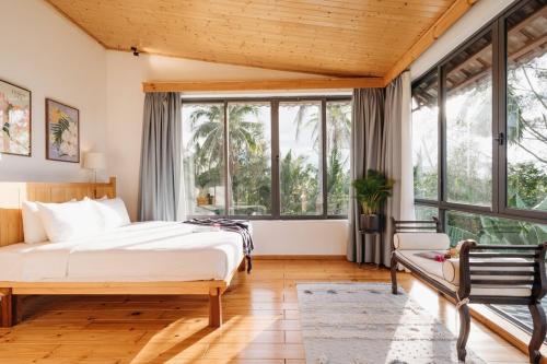 a bedroom with a large bed and large windows at Bong Villa Hoi An - Vesta Collections in Hoi An
