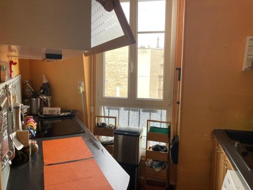 une cuisine avec un comptoir et une fenêtre dans l'établissement Paris Tour Eiffeio, cœur des JO, à Paris