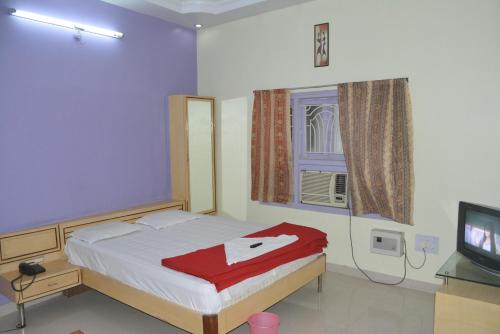 a bedroom with a bed and a tv and a window at Hotel Naveen Residency in Darbhanga