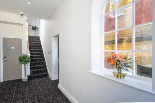 a hallway with a staircase with a window and a vase of flowers at Best Western Chiswick Palace & Suites London in London