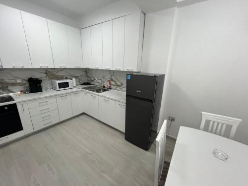 a kitchen with white cabinets and a black refrigerator at Lumiver Apartment in Golem