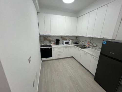a kitchen with white cabinets and a black refrigerator at Lumiver Apartment in Golem