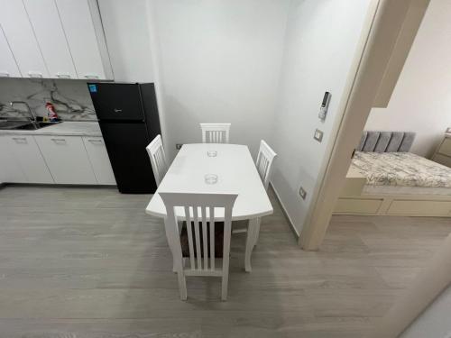 a kitchen with a white table and chairs and a bed at Lumiver Apartment in Golem