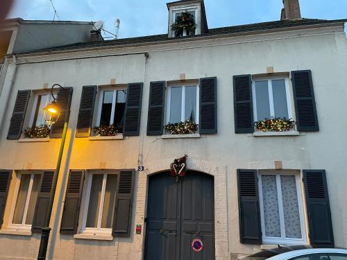 a building with black shuttered windows and a door at Les glycines in Bonneval