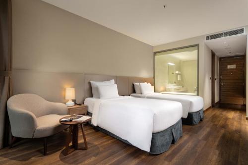 a hotel room with two beds and a chair at Flamingo Resort Cat Ba in Cat Ba