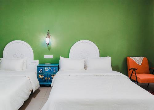 a green room with two beds and an orange chair at 达卜·九宿民宿 in Turfan