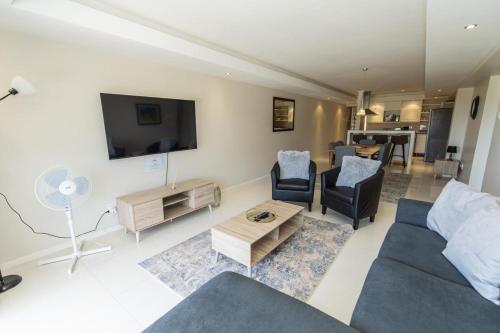 a living room with a couch and chairs and a tv at The Pearls 3b Luxury Apartment in Summerstrand