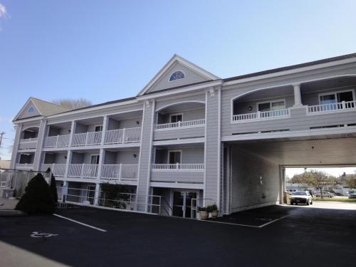 a large white apartment building with a parking lot at Hyannis Travel Inn in Hyannis