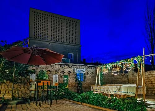 a patio with a table and an umbrella at night at 达卜·九宿民宿 in Turfan