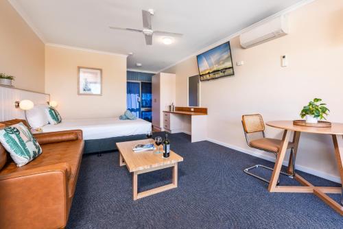 a hotel room with a bed and a couch and a table at South Seas Motel in Merimbula