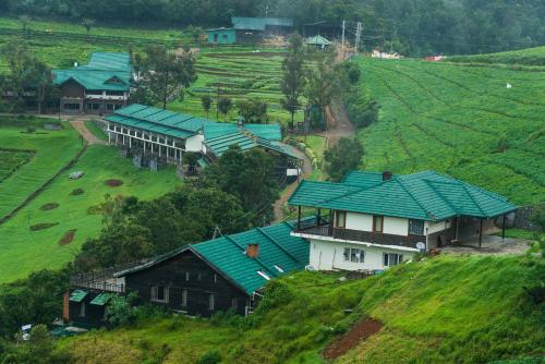 a house with green roofs on a hill at Destiny - The Farm Resort in Ooty