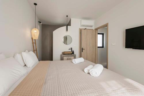 a bedroom with a large bed with two towels at Kouros Exclusive Hotel & Suites - Adults Only in Faliraki
