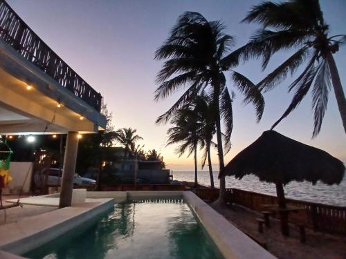 a swimming pool in front of a resort with palm trees at Casa con alberca frente del mar de Santa clara Yucatan in Santa Clara