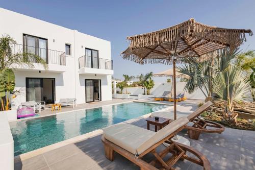 a villa with a swimming pool with a chair and an umbrella at Kouros Exclusive Hotel & Suites - Adults Only in Faliraki