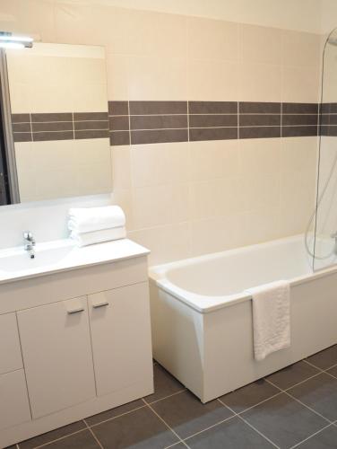 une salle de bain avec un lavabo, une baignoire et des toilettes dans l'établissement Hotel Les Acacias, au Grau-du-Roi