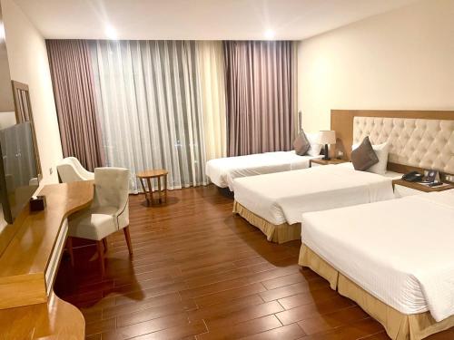 a hotel room with two beds and a table and chairs at Muong Thanh Cua Dong Hotel in Vinh