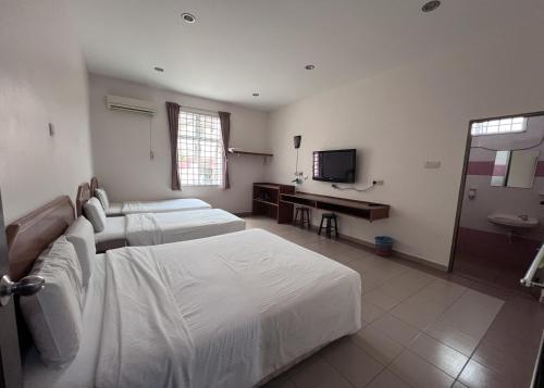 クアンタンにあるSL Villa Guesthouse, Kuantanのベッド2台とテレビがあるホテルの部屋