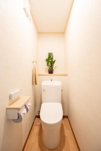 a bathroom with a toilet with a plant on the wall at Rise's House in Nishio