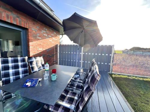 a table and chairs on a patio with an umbrella at Seelenwärmerstuuv in Kronprinzenkoog