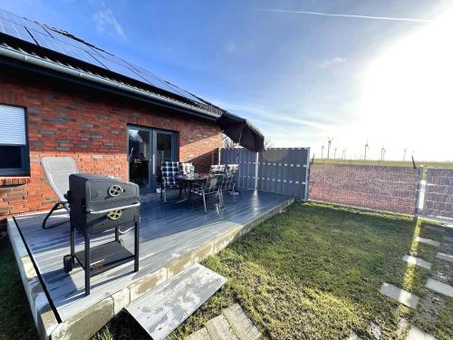 a deck with a grill and a table and chairs at Seelenwärmerstuuv in Kronprinzenkoog