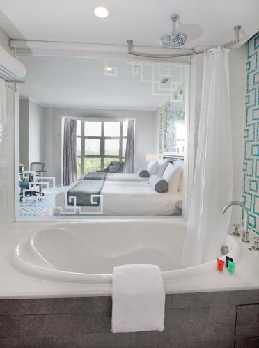 a bathroom with a tub and a bedroom with two beds at Dorsett Shanghai in Shanghai