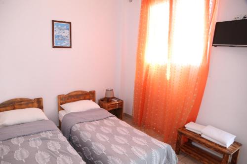 a room with two beds and a window with a curtain at Anais in Mýkonos City